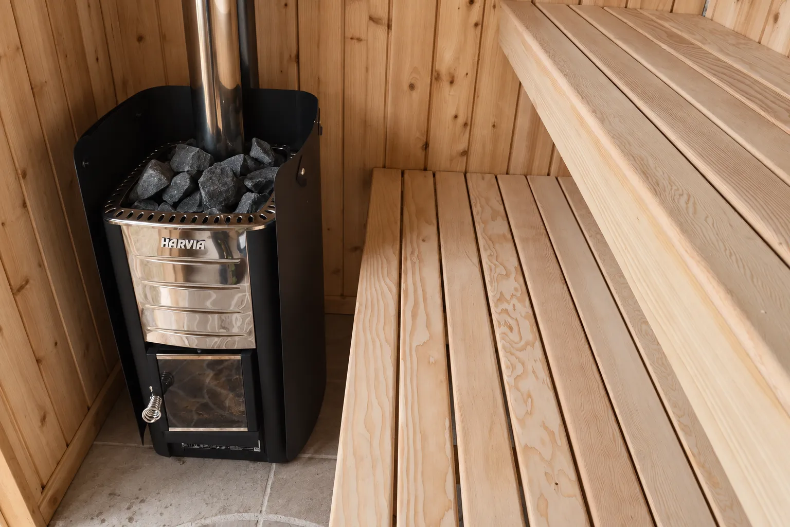 Natural timber benches and a wood-burning heater inside the sauna